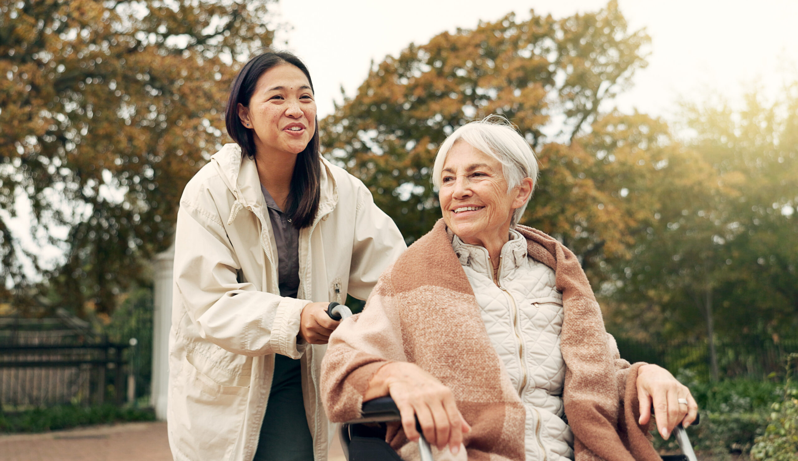 Young woman pushing elderly woman in wheelchair